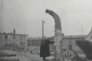 Narożny słup ogrodzenia obozu, o który wspiera się były więzień podobozu Neu Dachs Wiktor Pasikowski, który - razem z Włodzisławem Śmigielskim - uciekł z obozu 29 listopada 1944 r. Zdj. Nr. 4, stan z dn. 11.3.1959 r. Fot. T. Szymański. Ze zbiorów Archiwum Państwowego Muzeum Auschwitz - Birkenau.